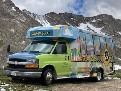 A photo of the Roundabout bus in front of mountains.