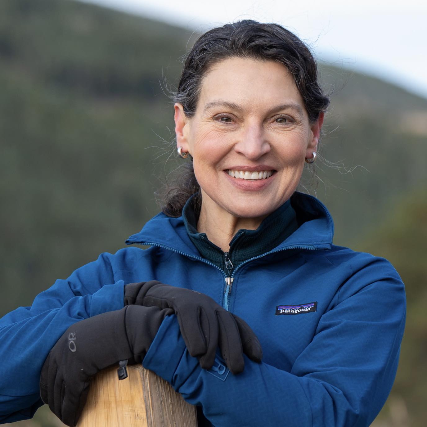 A close up of Commissioner Lloyd in a blue coat with mountains in the background.
